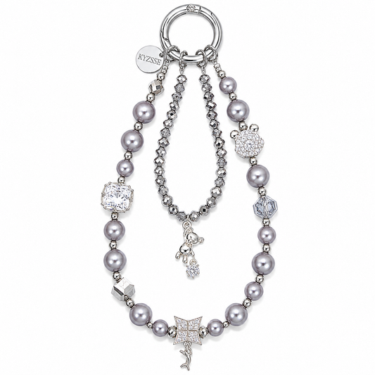A silver-tone key ring bag featuring gray faux pearls, a beaded chain, a crystal-embellished bracelet, and multiple charms including a mermaid, a fish, a flower, and a crown, with the brand name 'KYZSSE' visible on a round tag.