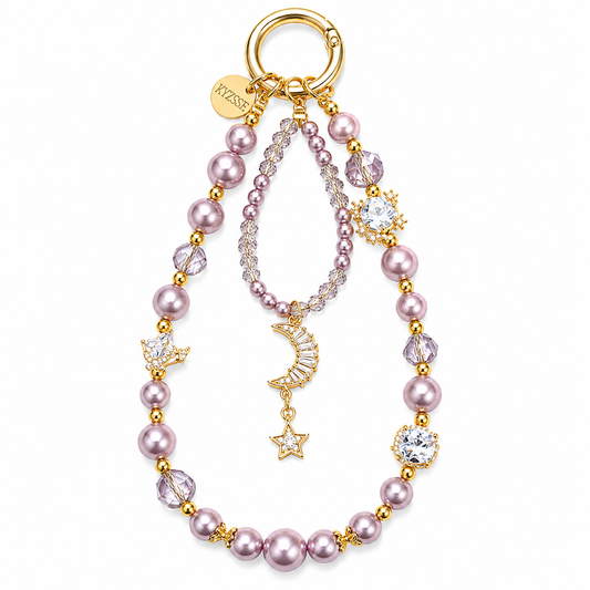 A gold-tone keychain or bag charm featuring pink faux pearls, clear faceted crystals, and celestial charms including a crescent moon, star, and sunburst, with a round gold ring at the top. The brand name 'KYZSSE' is visible on a small gold tag.