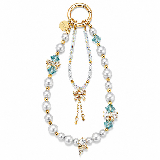 A gold-tone key ring bag charm featuring a pearl bead chain, light blue faceted crystal accents, a bow-shaped crystal charm, and a central dangling chain with a crystal-encrusted bow pendant, shown on a plain white background.